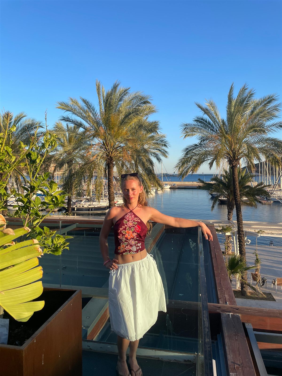 Celeste, the laureate, smiling at a sunlit marina among palm trees
